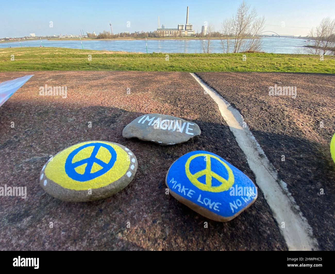 Peace steht auf den Steinen in den ukrainischen Landesfarben. Kinder haben die bemalten Steine am Rheinufer in Düsseldorf abgelegt. Stock Photo