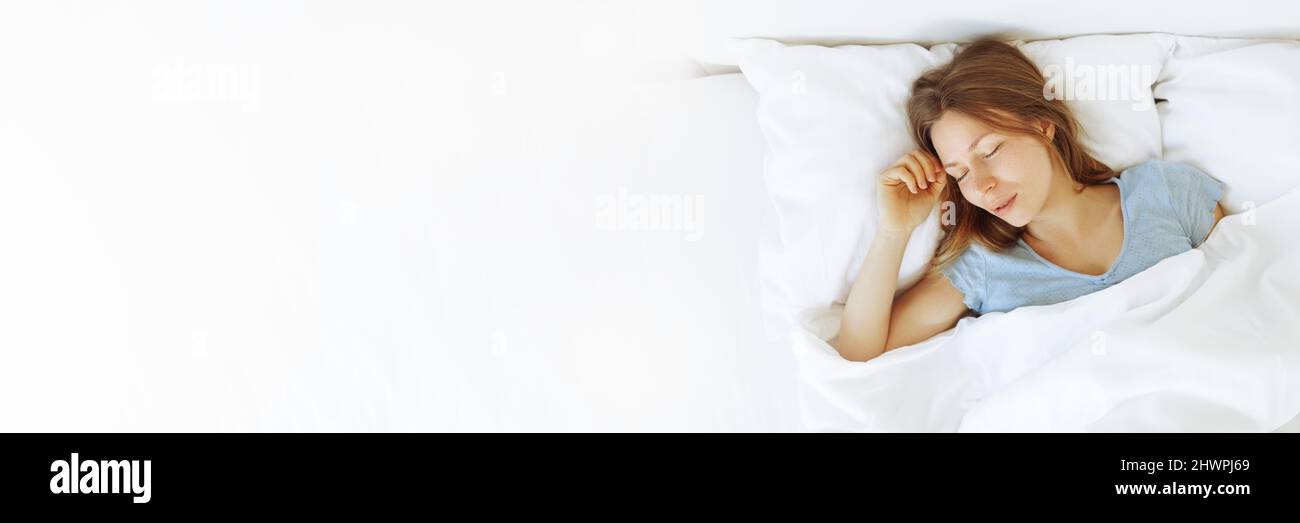 Banner of young woman enjoying sleeping time in bed , close up ,elevated view, hugging pillow. Stock Photo