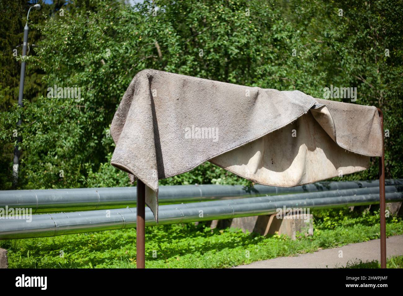 Wet carpet is drying outside. Cloth thing hangs on pole. Natural drying of  rug in sunlight Stock Photo - Alamy