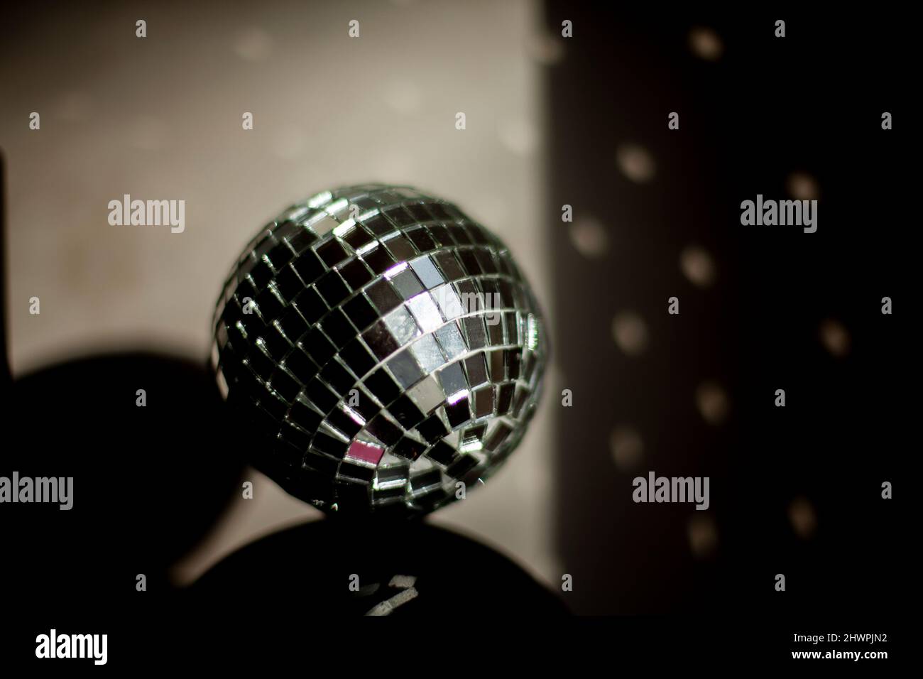 Disco ball reflects light in room. Ball of small mirrors stands on