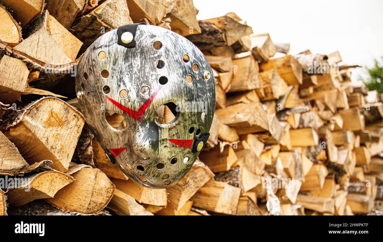 Creepy steel hockey mask lays on the ground near with woods Stock Photo