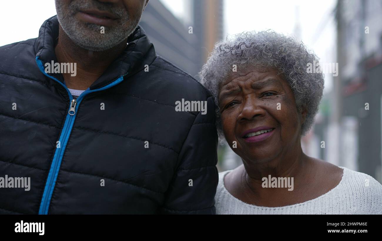A son and senior mother walking together in street 80s parent Stock