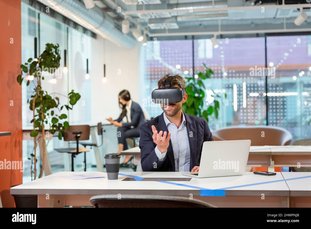 Employee with VR googles gesturing in office Stock Photo