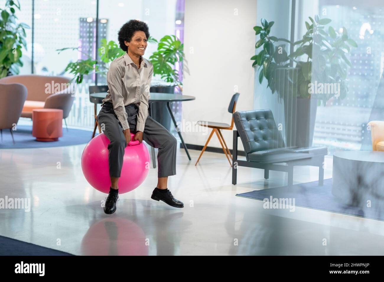 Manager bouncing on hopper ball in office Stock Photo