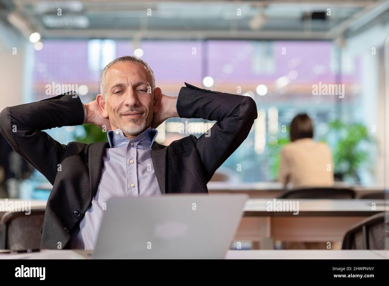 Businessman with hands behind head relaxing in office Stock Photo