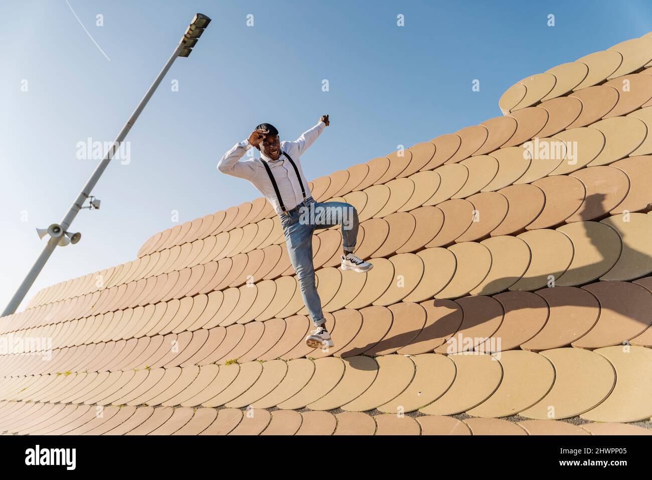 Young man jumping over roofing tiles on sunny day Stock Photo