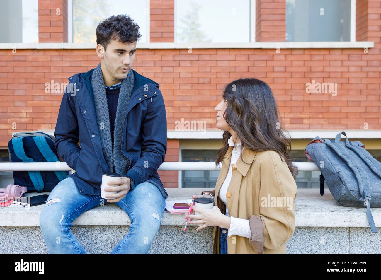 Students talking with disposable cup on college campus Stock Photo