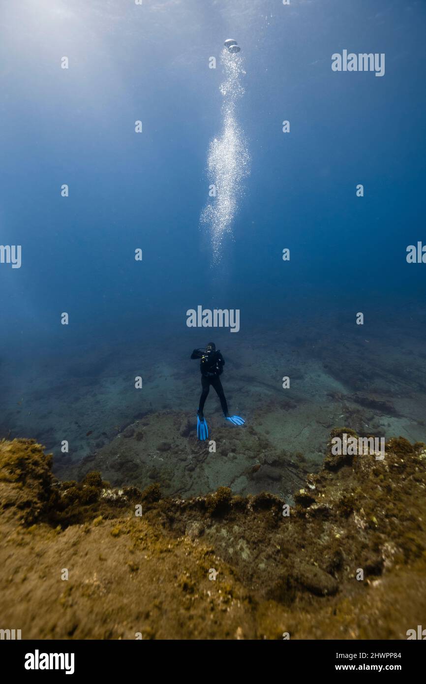 Woman scuba diving over ocean floor in blue sea Stock Photo