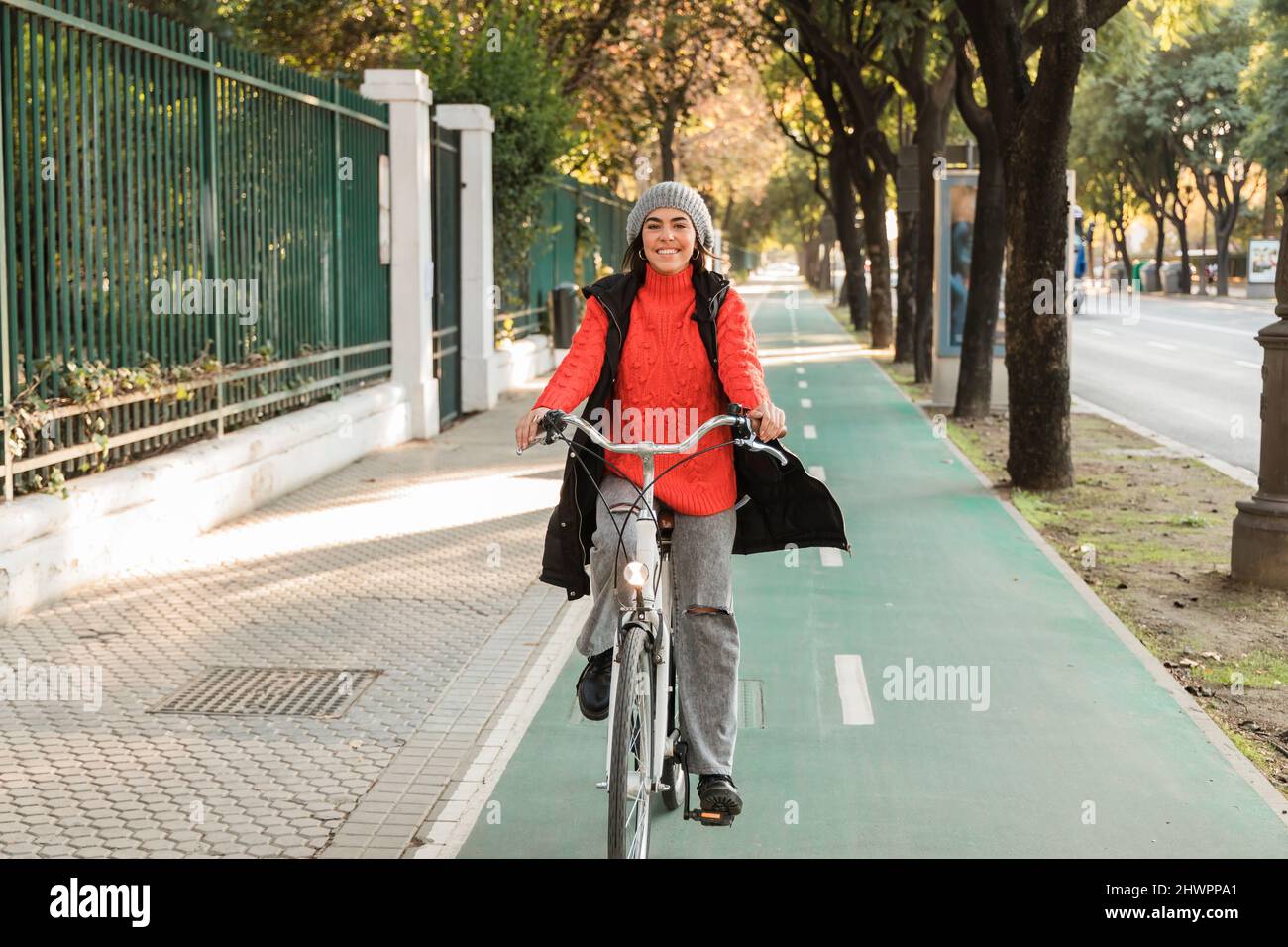 Smiling young woman cycling on bicycle lane Stock Photo