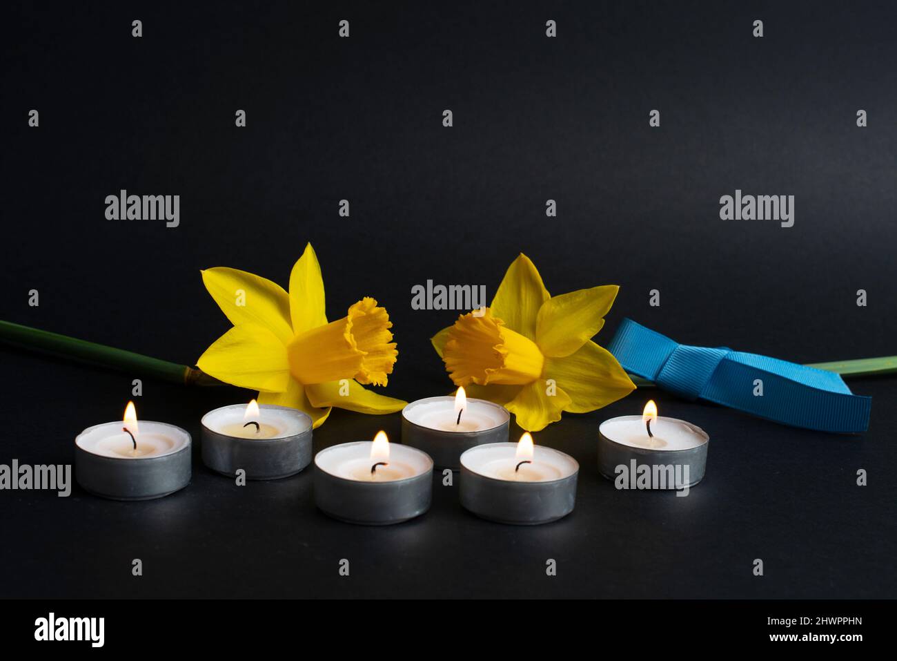 Pray for Ukraine. Burning candles, yellow flowers and blue ribbon. Stop