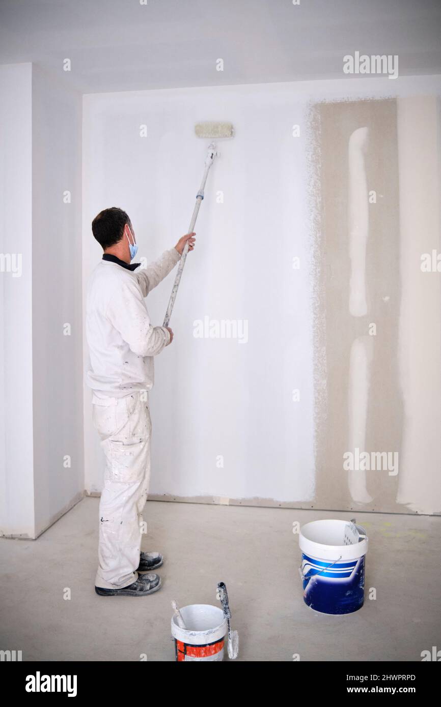 House painter painting wall with roller at construction site Stock Photo