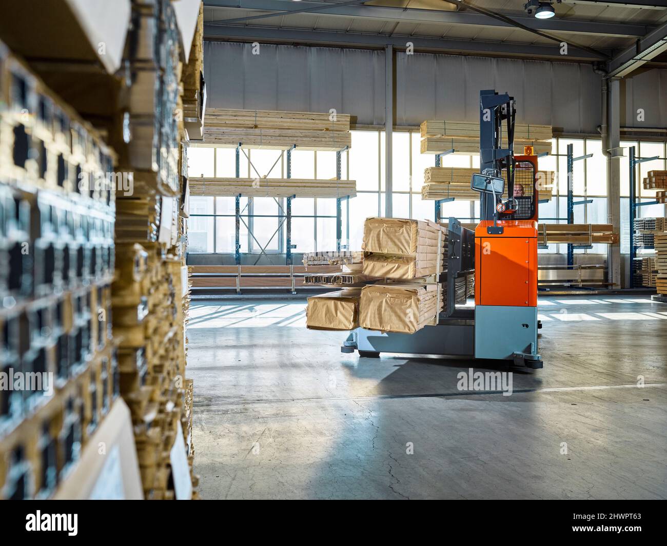 Warehouse worker operating forklift in industrial building Stock Photo