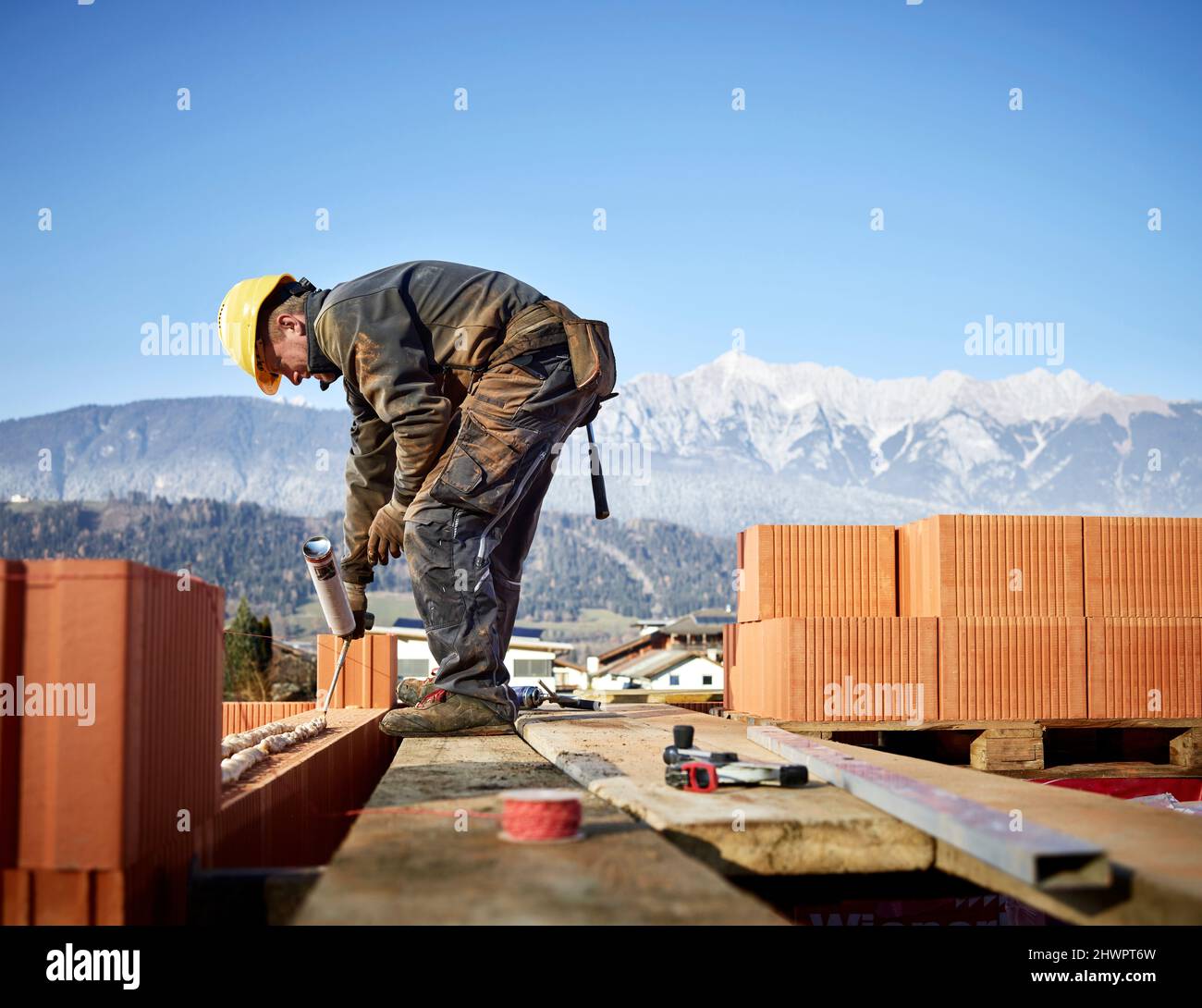 Bricklayer fixing bricks with glue holding caulk gun at construction site Stock Photo