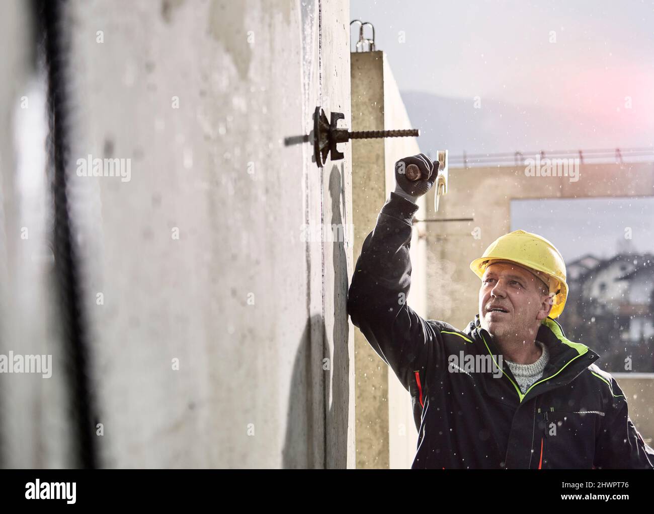 Worker with hammer loosening iron rod on concrete wall Stock Photo