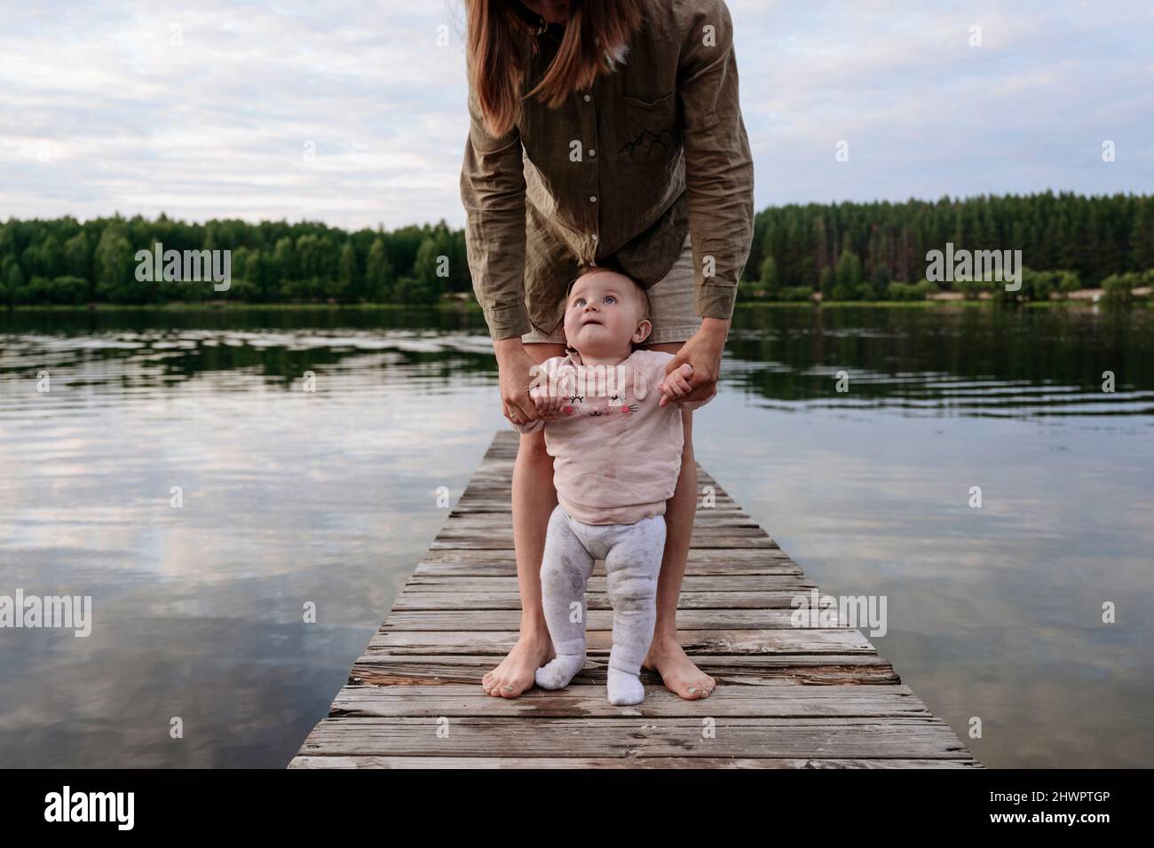 Mother holding hands of toddler walking on jetty Stock Photo