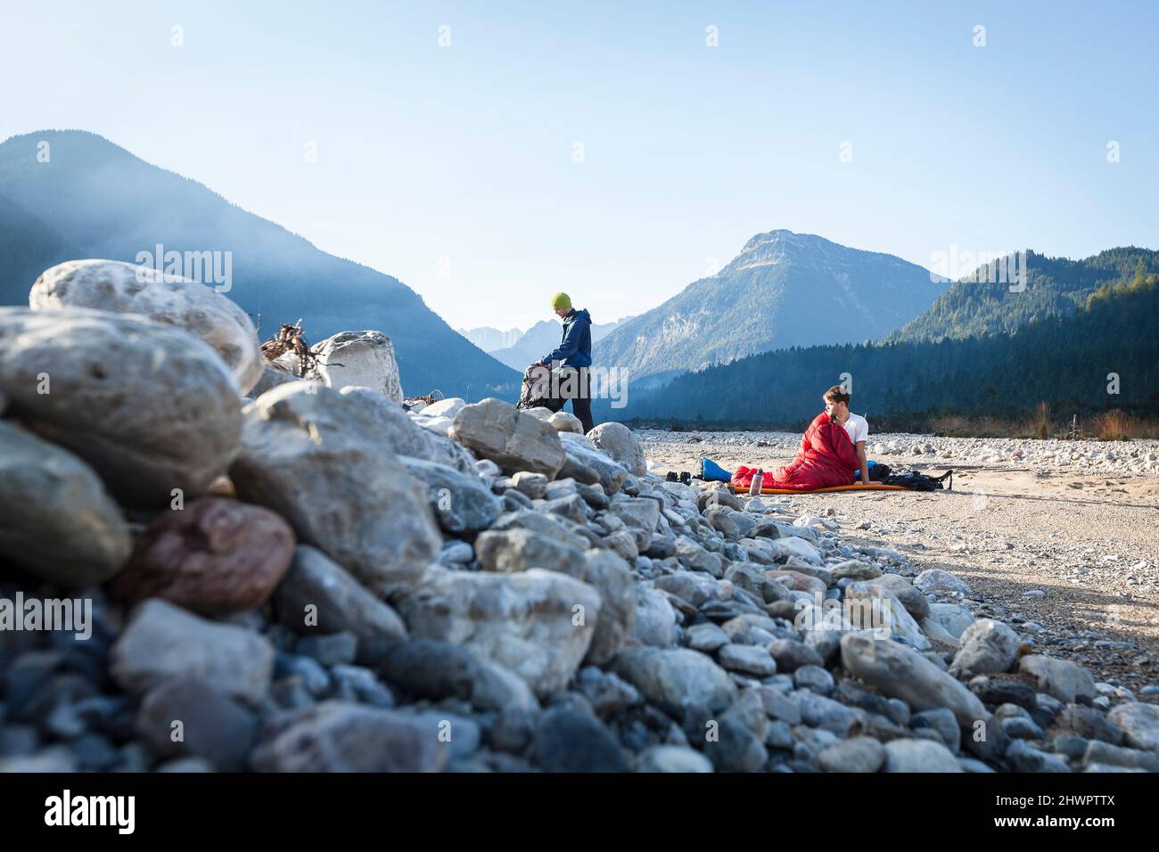 Man in bivouac looking at friend packing backpack on vacation, Karwendel Mountains, Bavaria, Germany Stock Photo