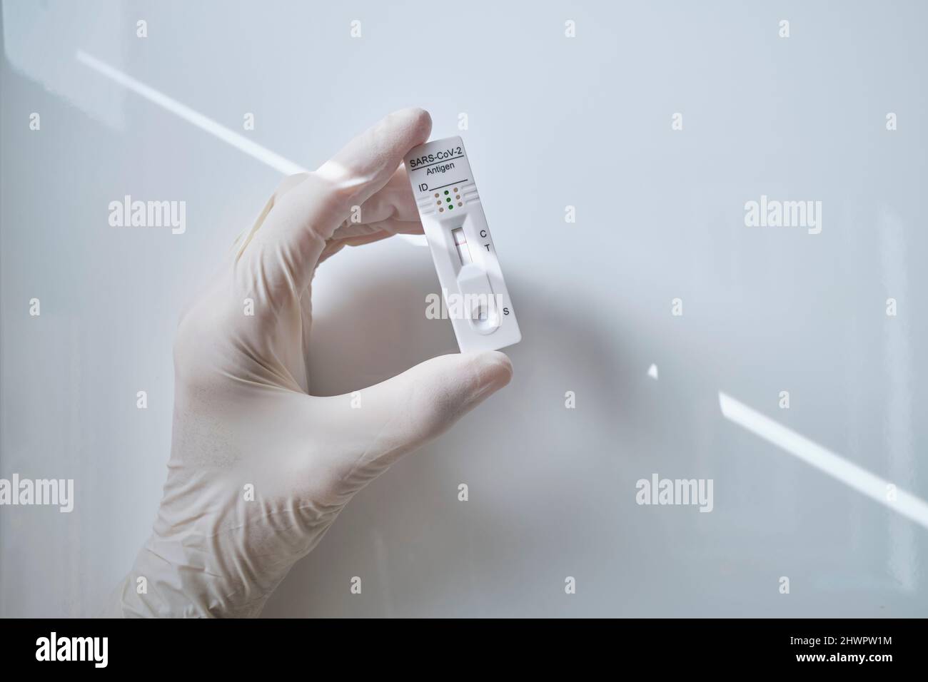 Hand holding rapid diagnostic device showing COVID-19 negative results against white background Stock Photo