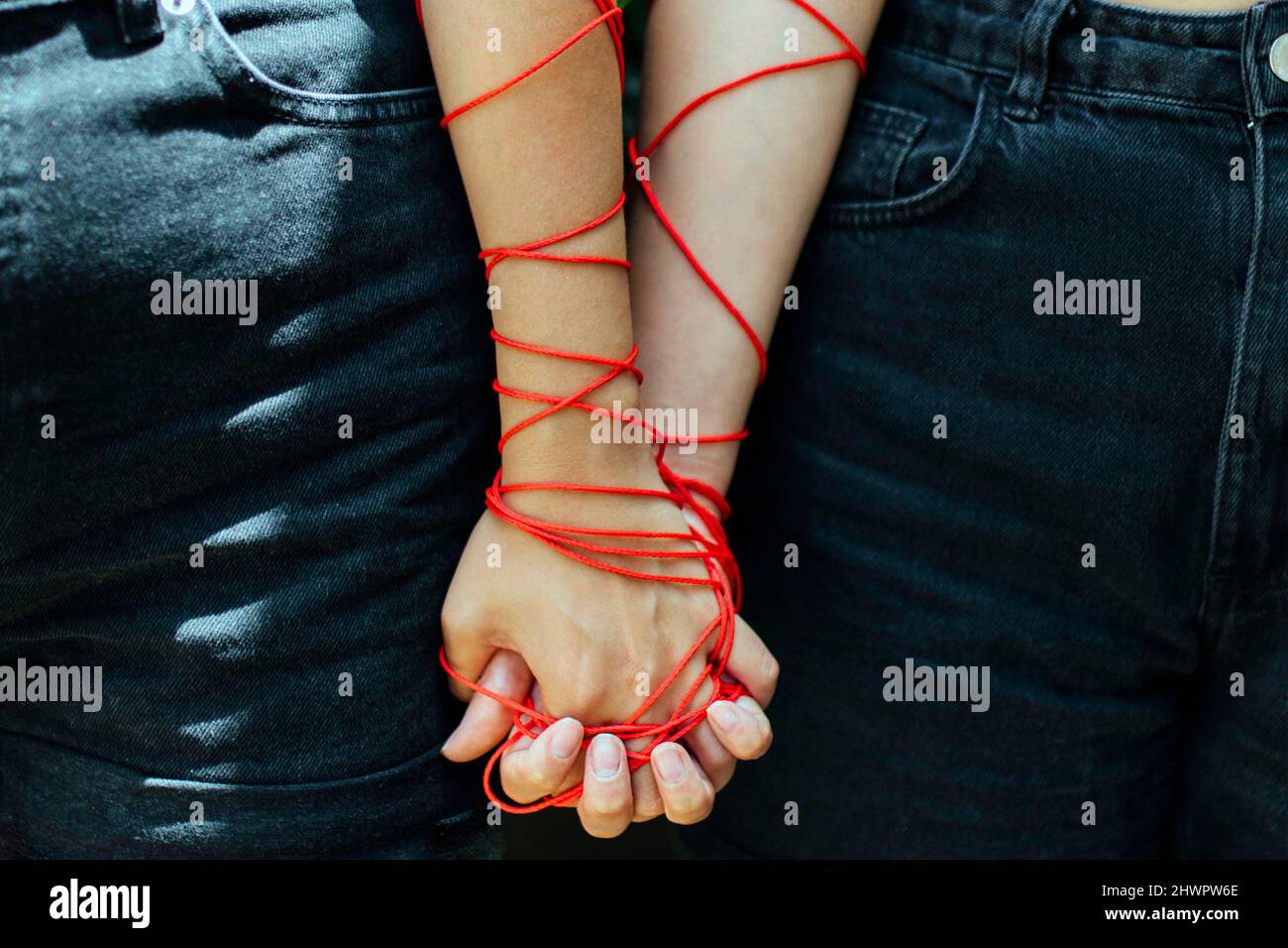 Two women with thread holding hands Stock Photo - Alamy