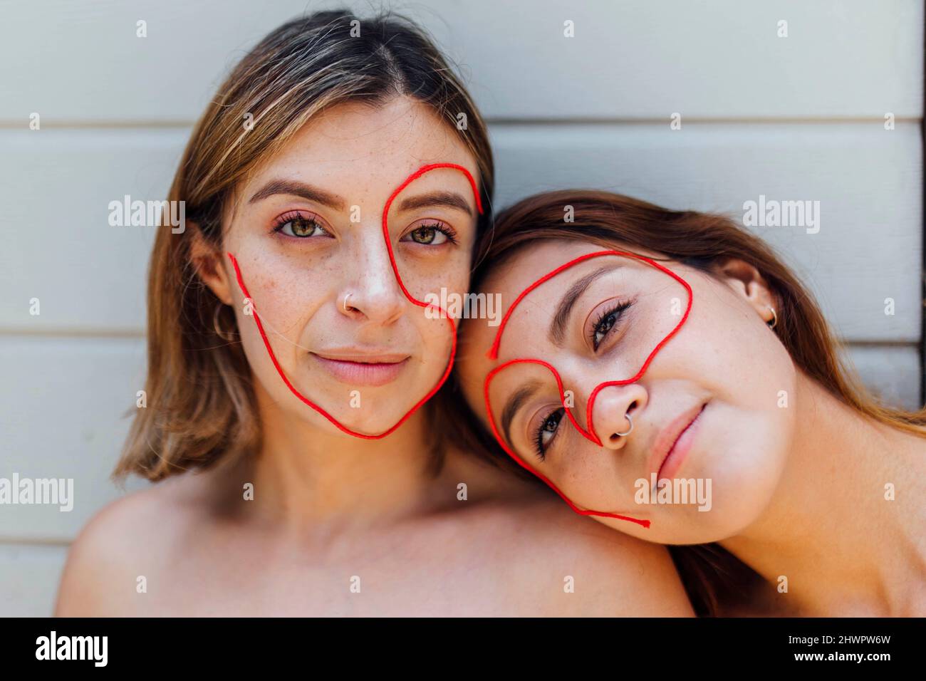 Young women with thread on face in front wall Stock Photo - Alamy