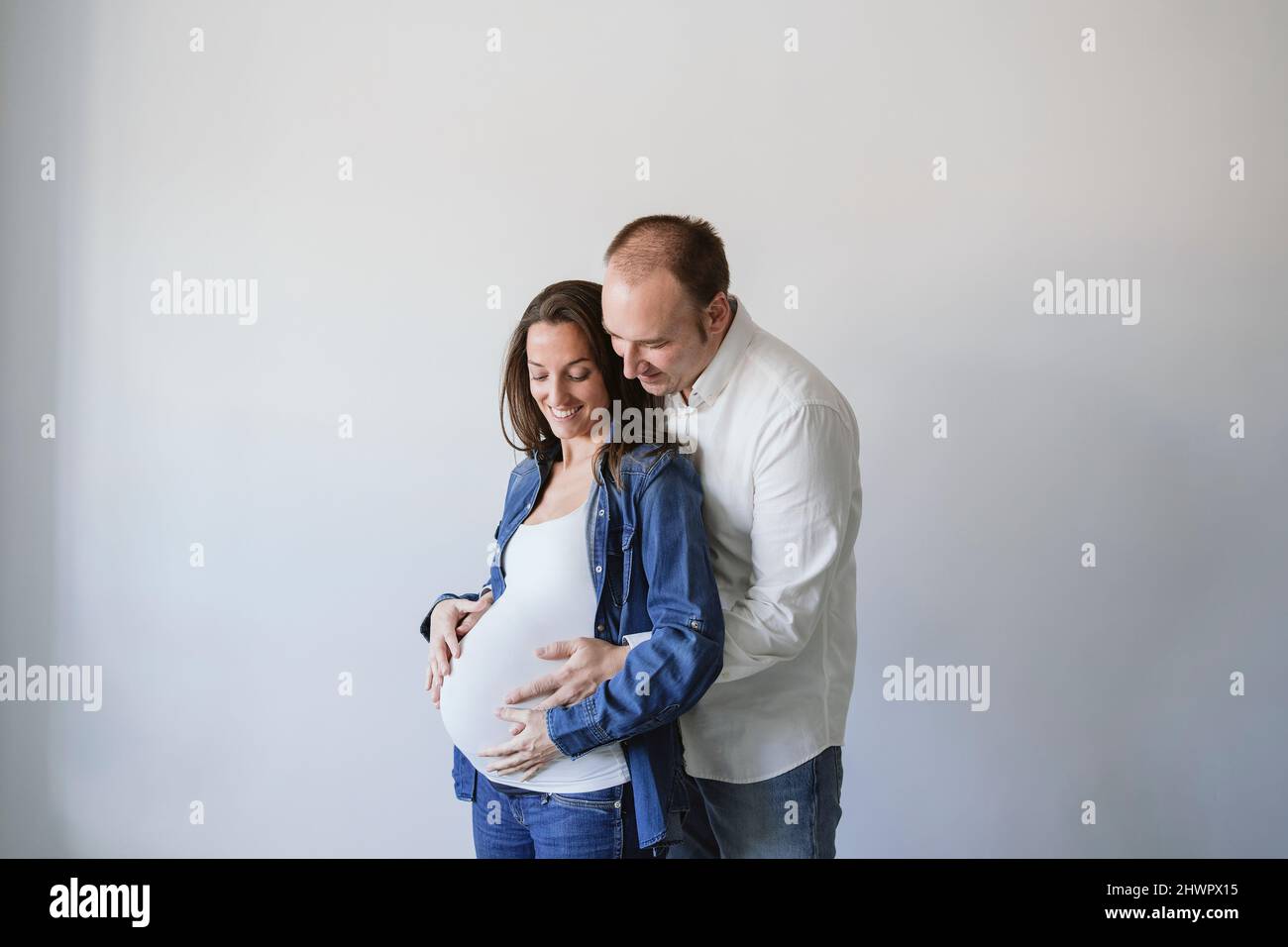 Man hugging happy pregnant woman by wall Stock Photo - Alamy