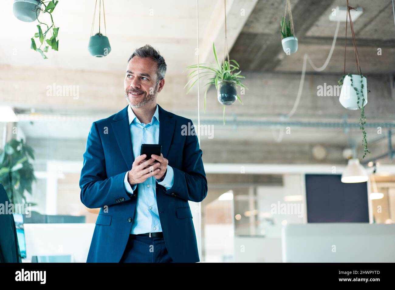 Smiling businessman using mobile phone at workplace Stock Photo