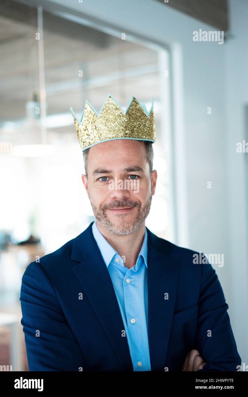 Smiling businessman wearing crown at workplace Stock Photo