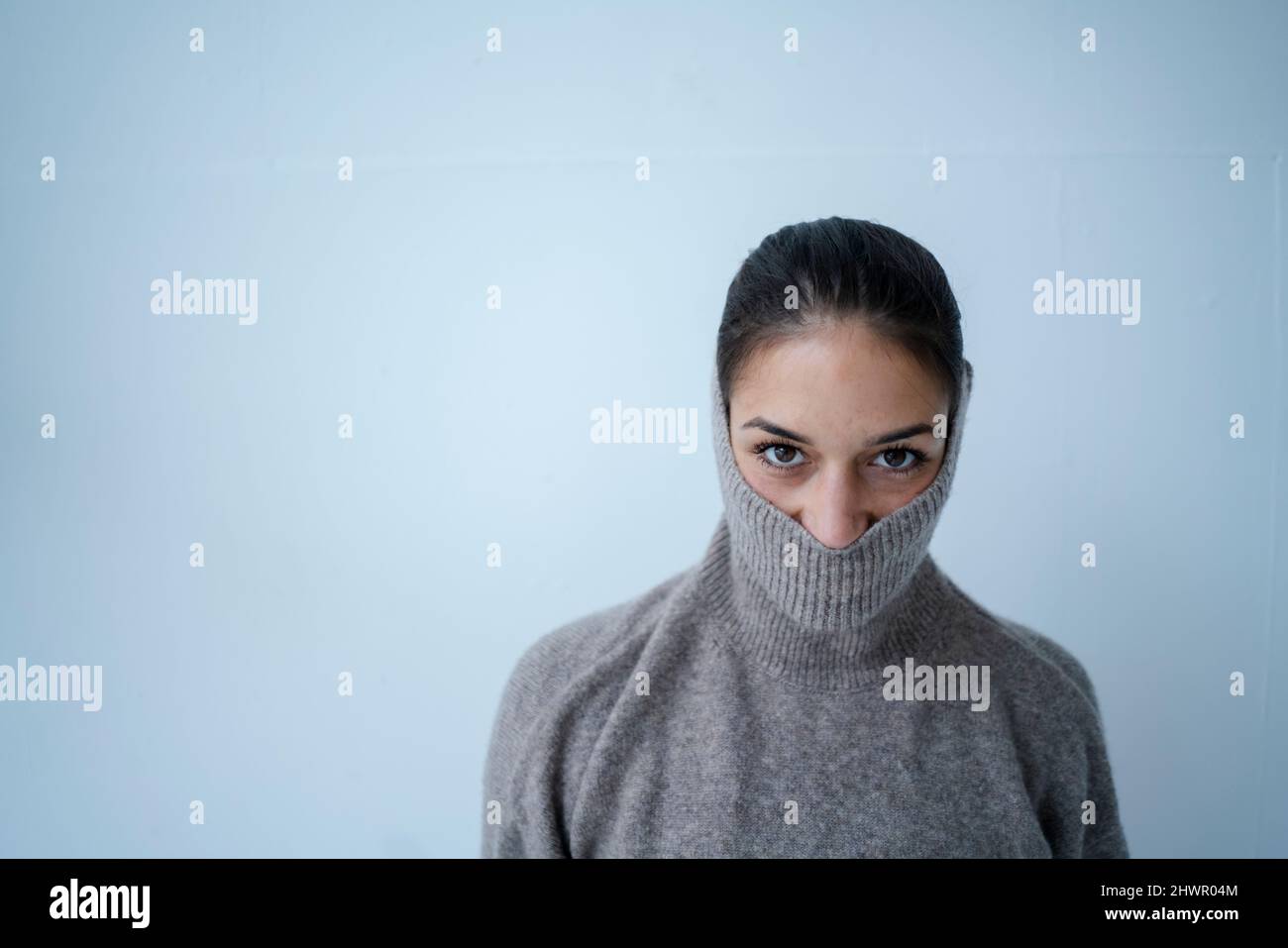 Woman covering face with gray sweater in front of wall Stock Photo - Alamy