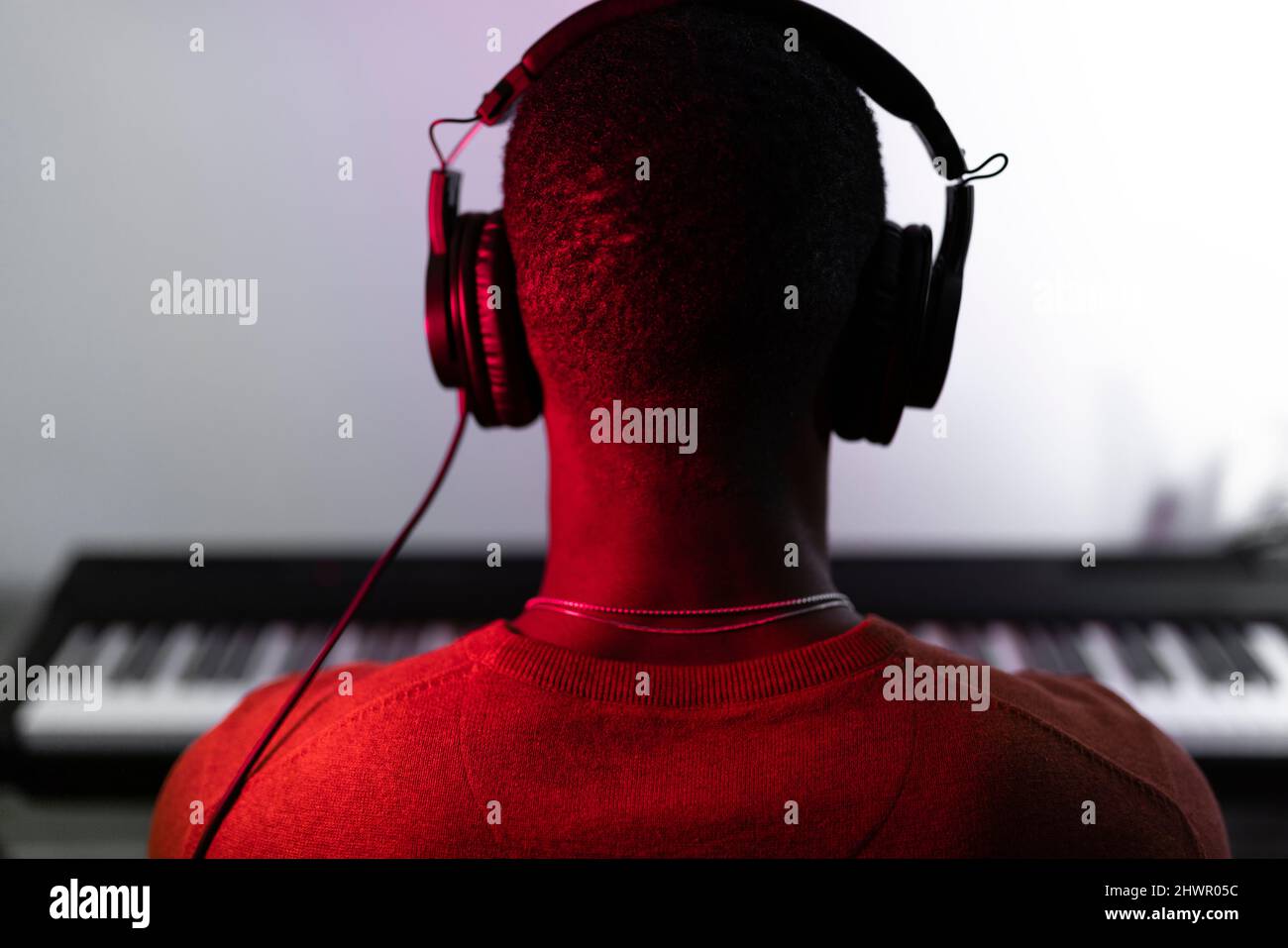 Man wearing headphones in front of piano Stock Photo