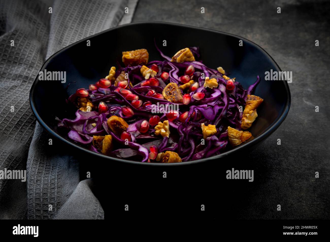 Studio shot of bowl of vegan salad with red cabbage, pomegranate seeds, dried figs and walnuts Stock Photo