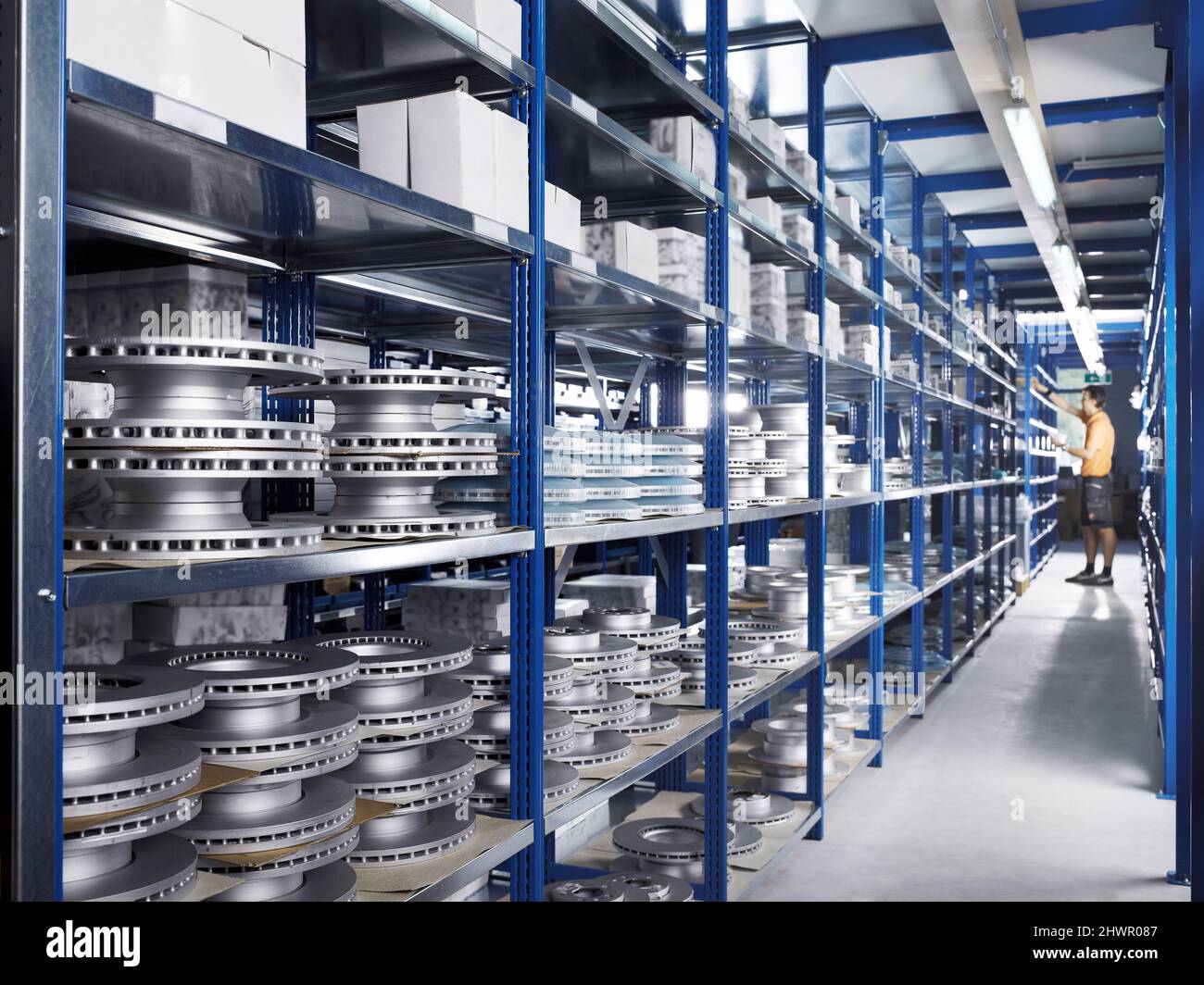 Technician in repair shop alley amidst racks with spare parts Stock Photo