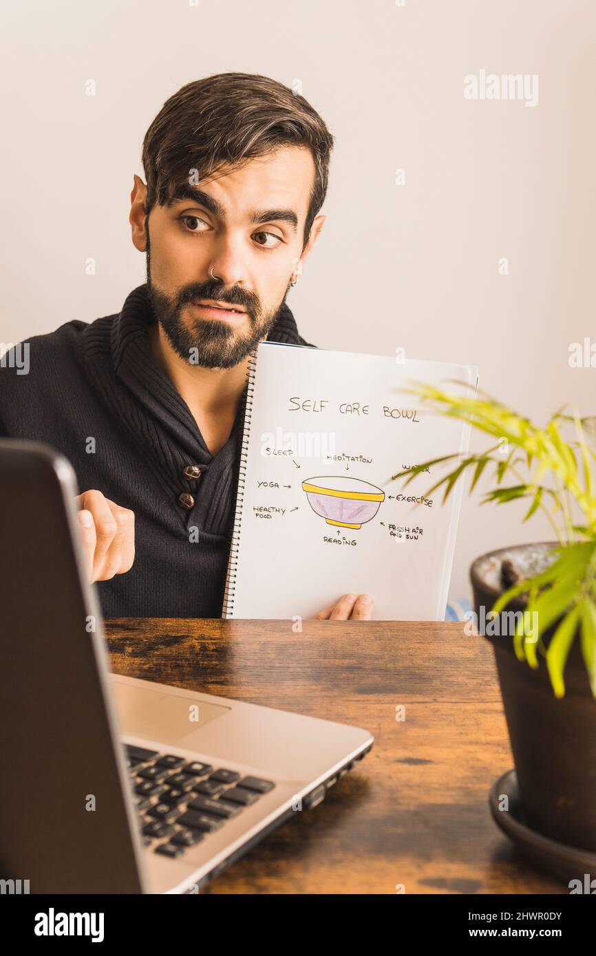 Young psychologist showing notebook about self care topics through online therapy Stock Photo