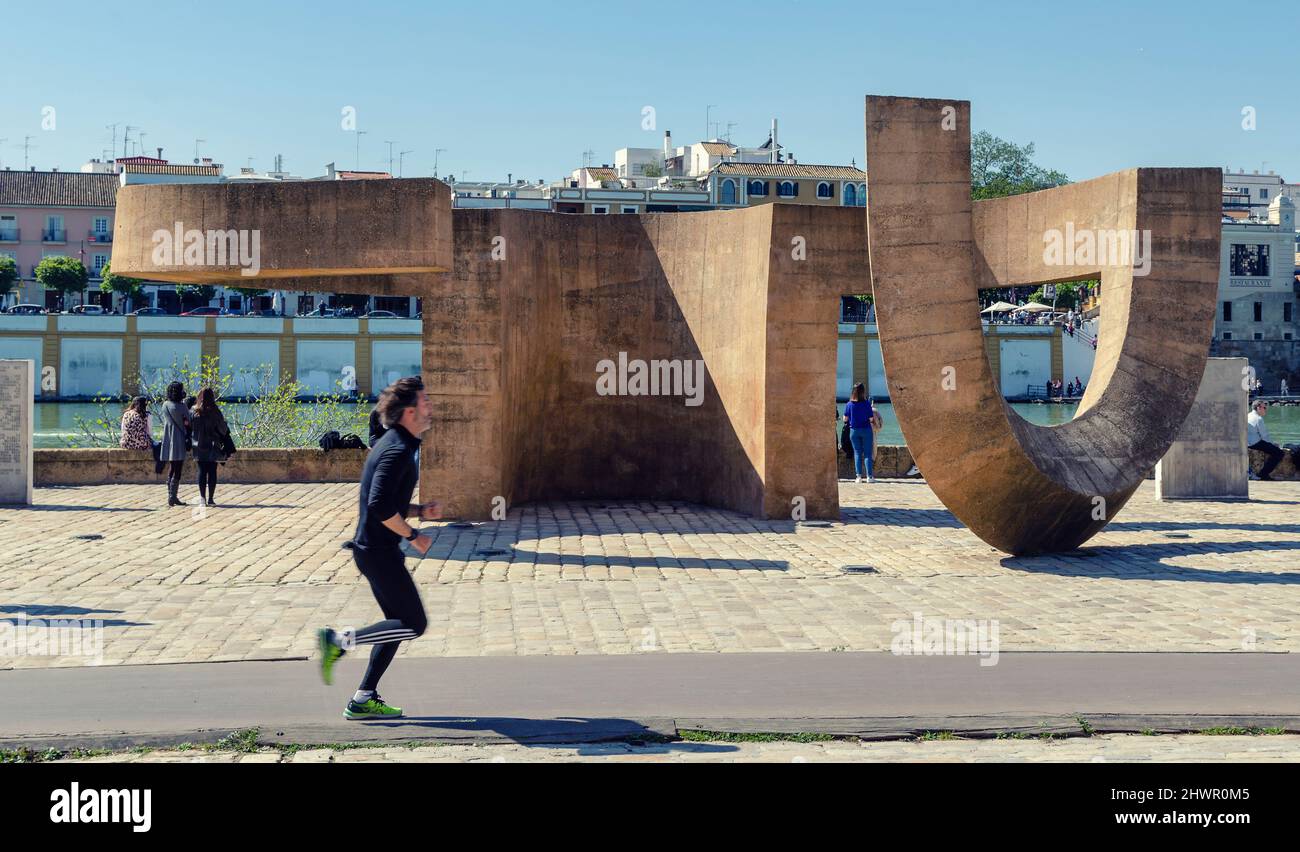 Monument to tolerance by the sculptor Eduardo Chillida alongside the Guadalquivir river. Man running and people enjoying a sunny day. Stock Photo