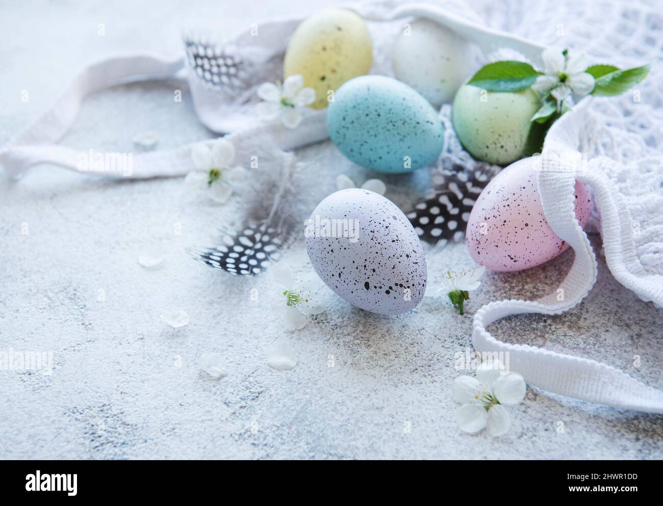 String bag with Easter eggs and spring blossom on concrete background Stock Photo