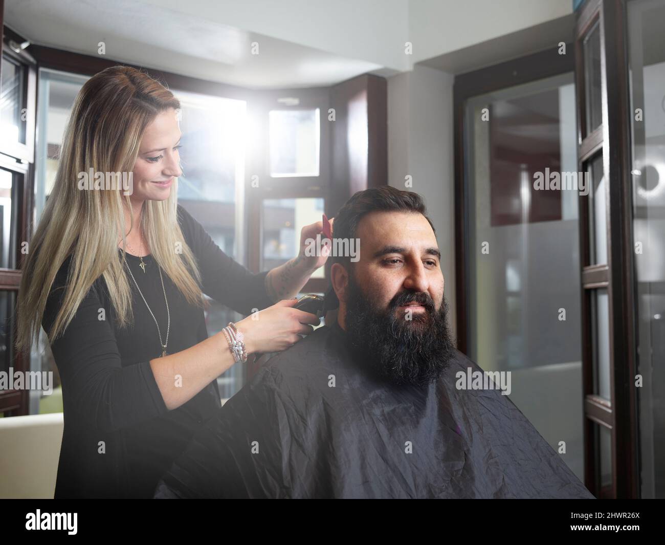 Hairstylist cutting man's hair using electric razor at salon Stock ...