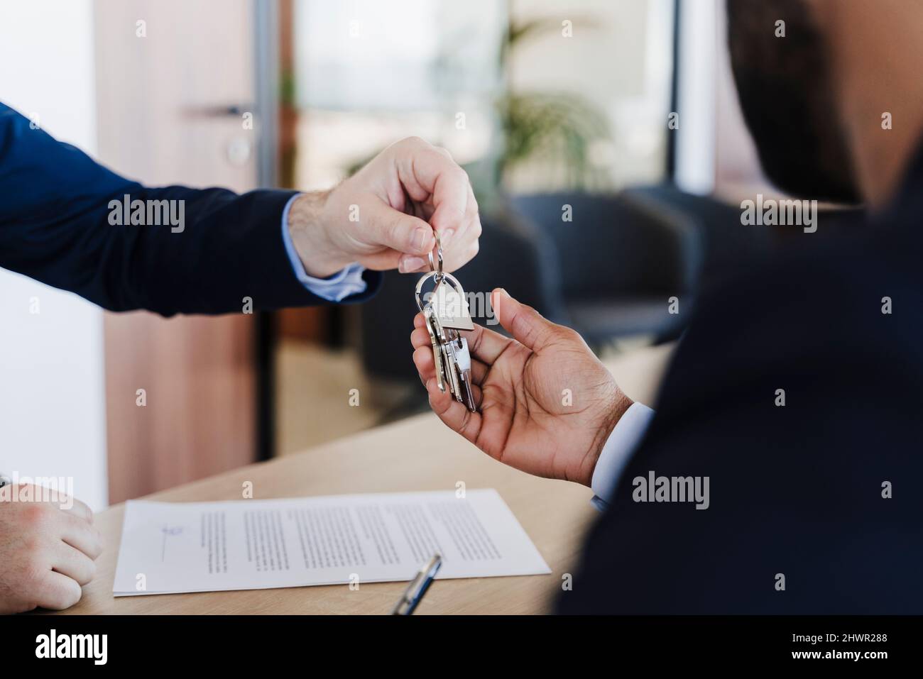Real estate agent giving house keys to buyer in office Stock Photo