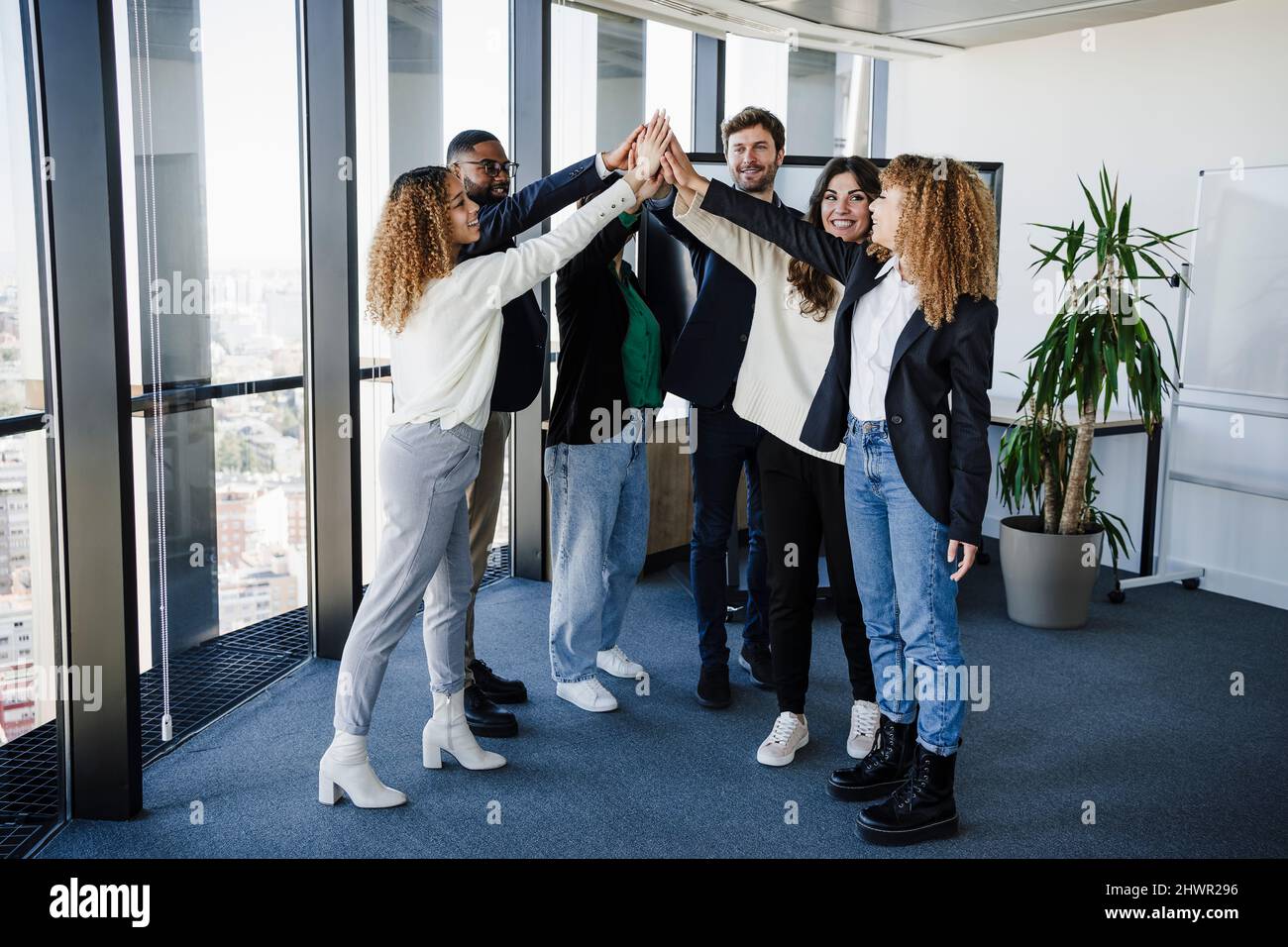 Multi-ethnic business colleagues stacking hands in office Stock Photo