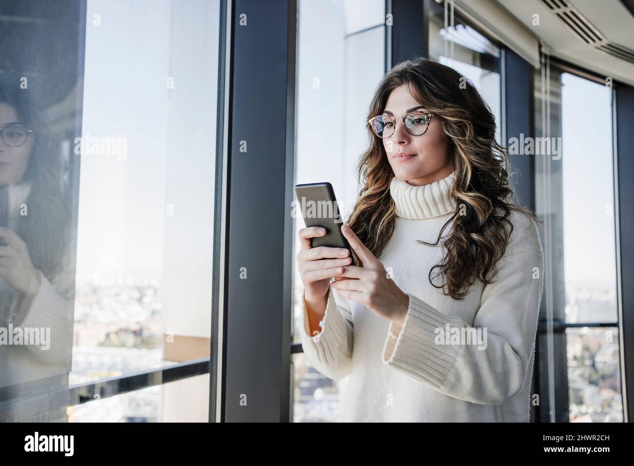 Businesswoman with wavy hair using smart phone in office Stock Photo
