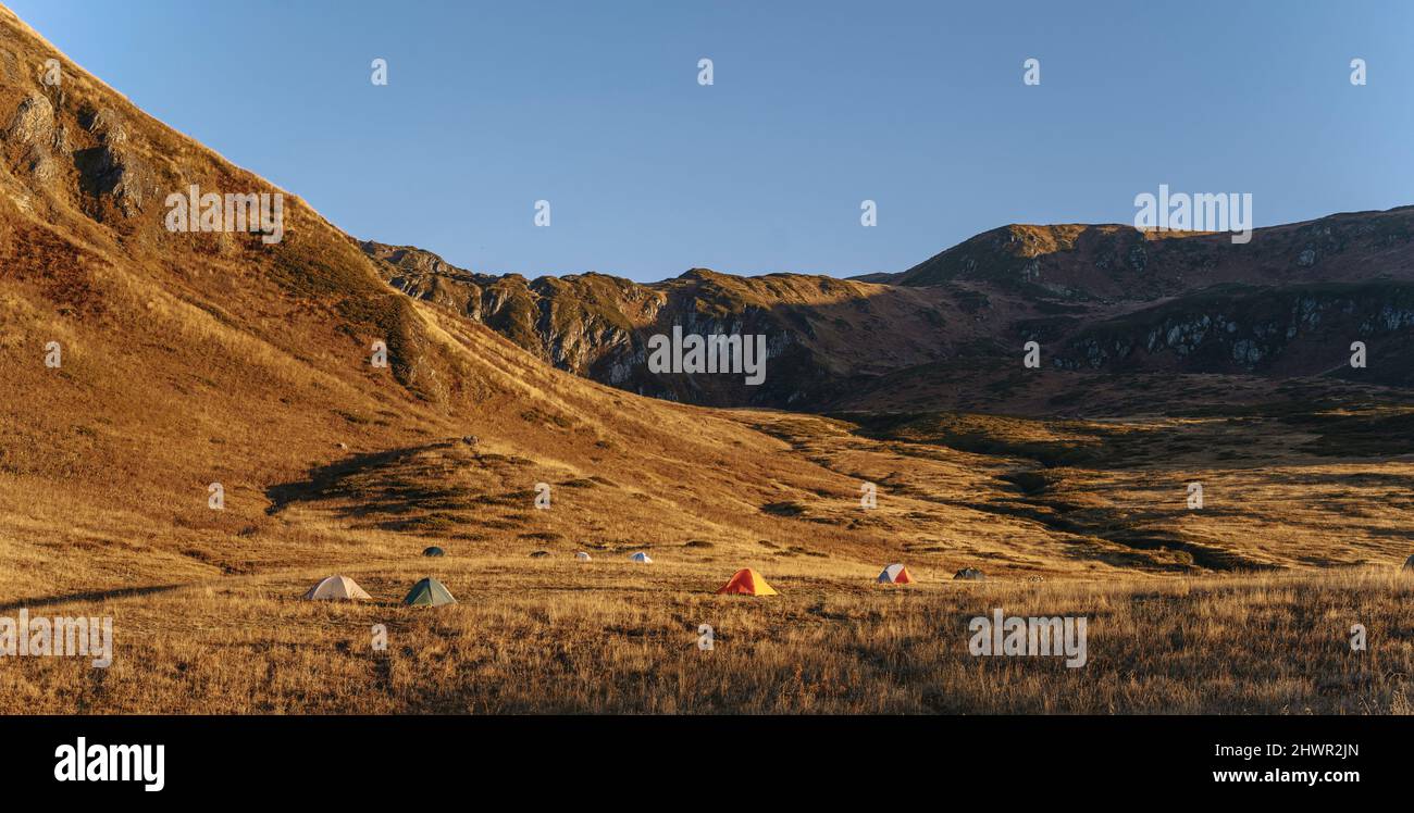 Tents on brown landscape by mountains, Caucasus, Sochi, Russia Stock Photo