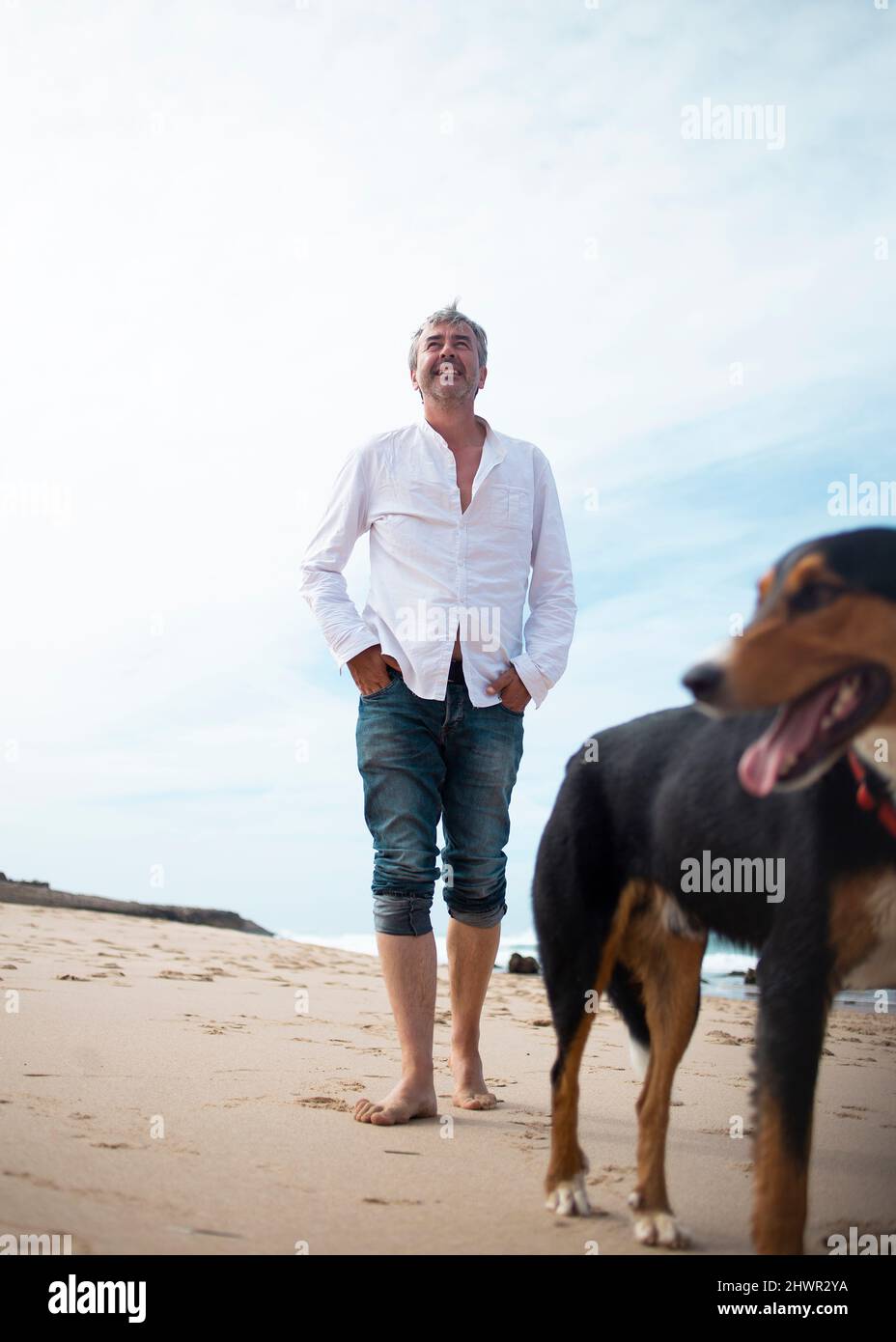 Happy man walking with dog on beach Stock Photo