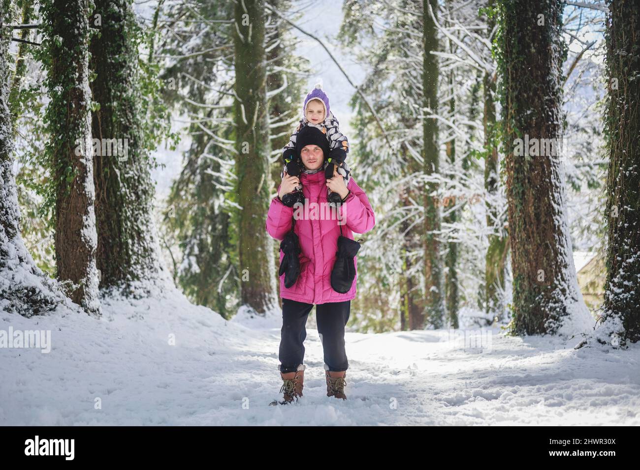 Father carrying daughter on shoulders in pine forest Stock Photo