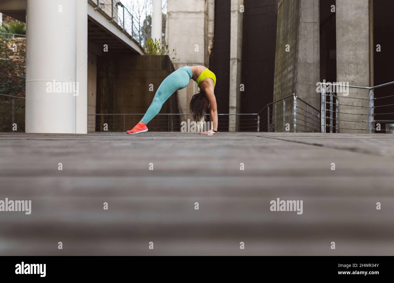 Young athlete bending over backwards on footpath in park Stock Photo