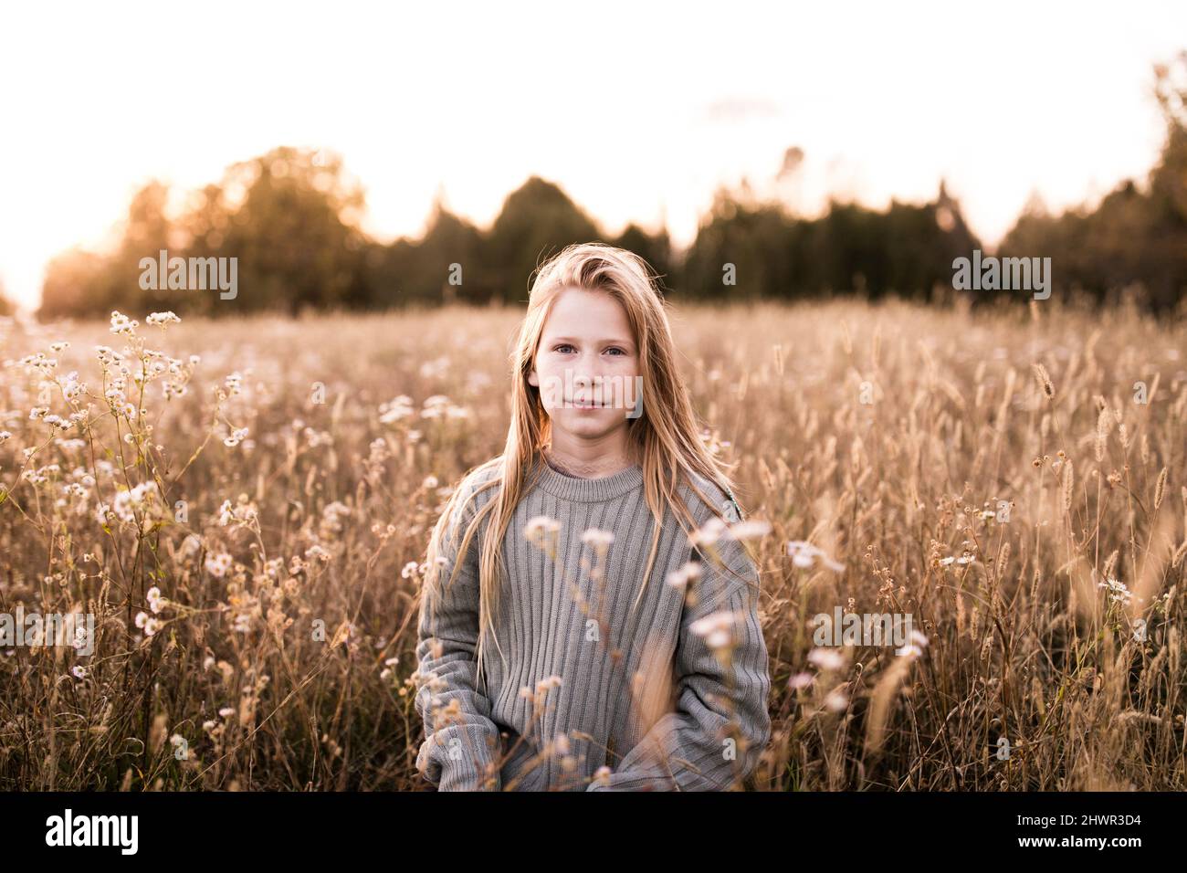 Blond girl with long blond hair standing at wildflower field Stock Photo
