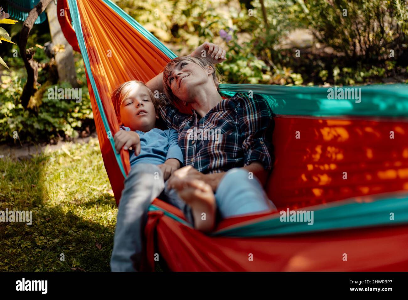 Mother day dreaming by son sleeping in hammock Stock Photo