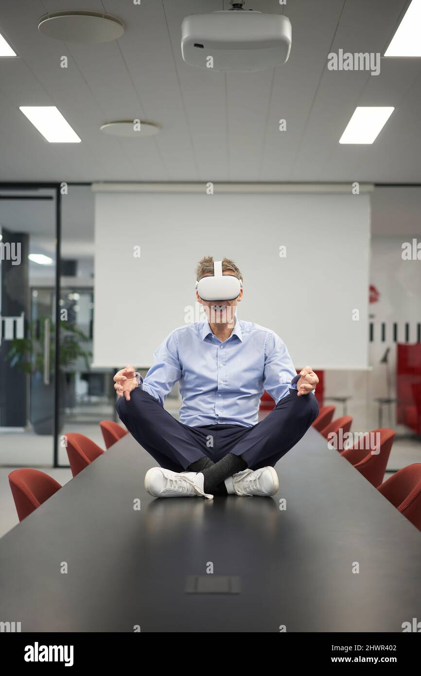Businessman wearing VR glasses sitting on conference table in meeting