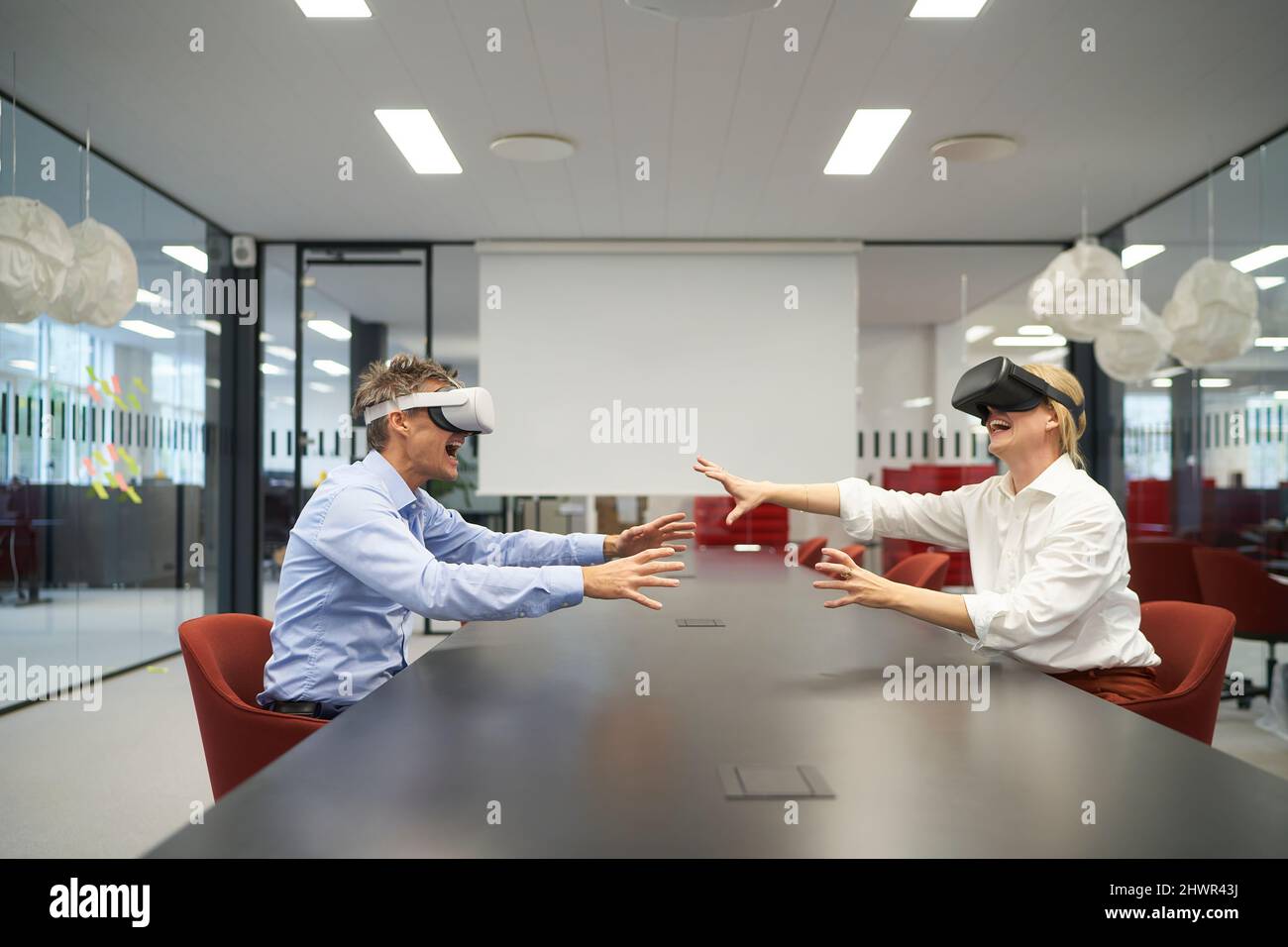 Colleagues using VR glasses sitting at conference table in office Stock Photo