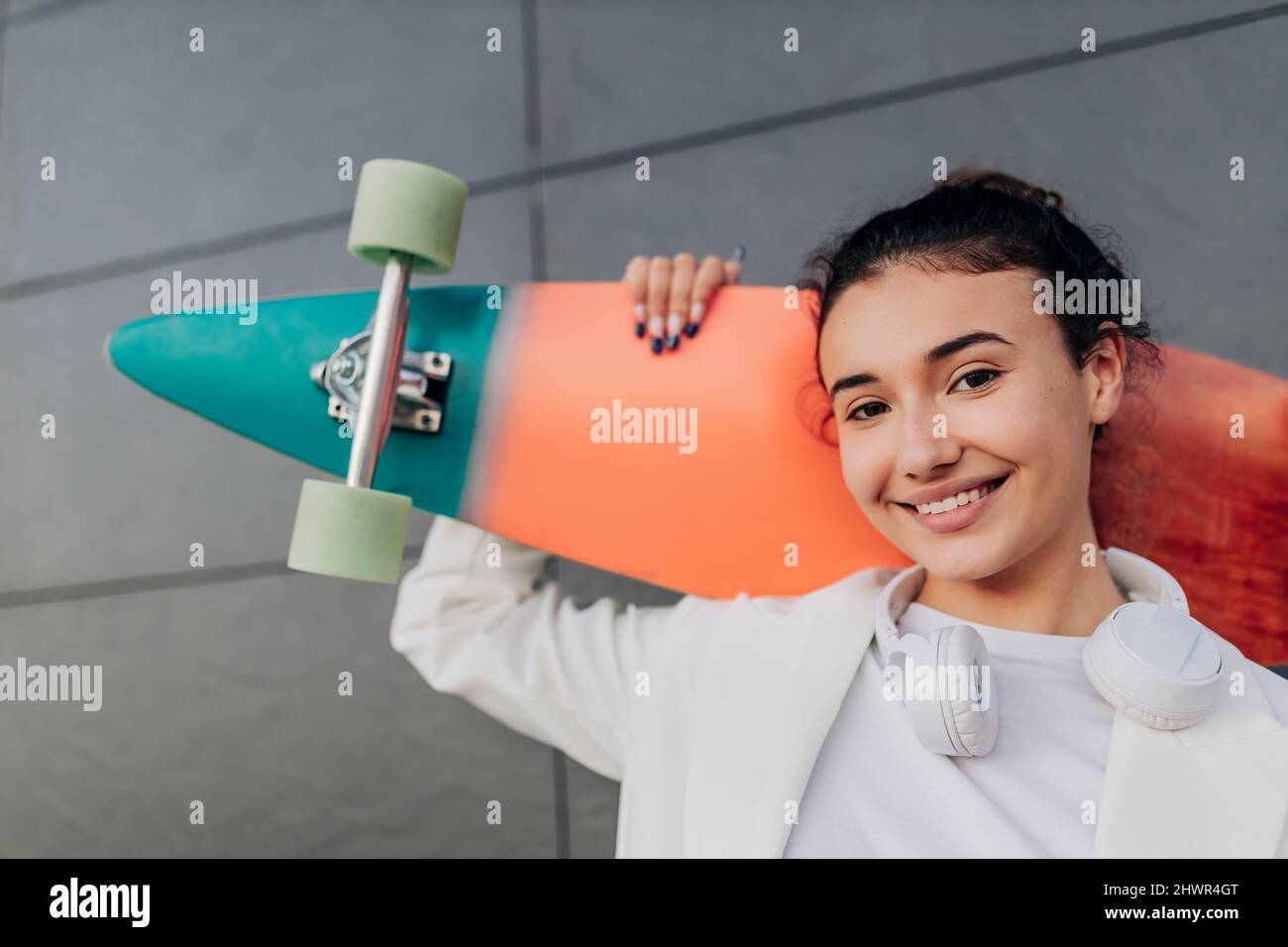 Smiling young woman with multi colored skateboard Stock Photo