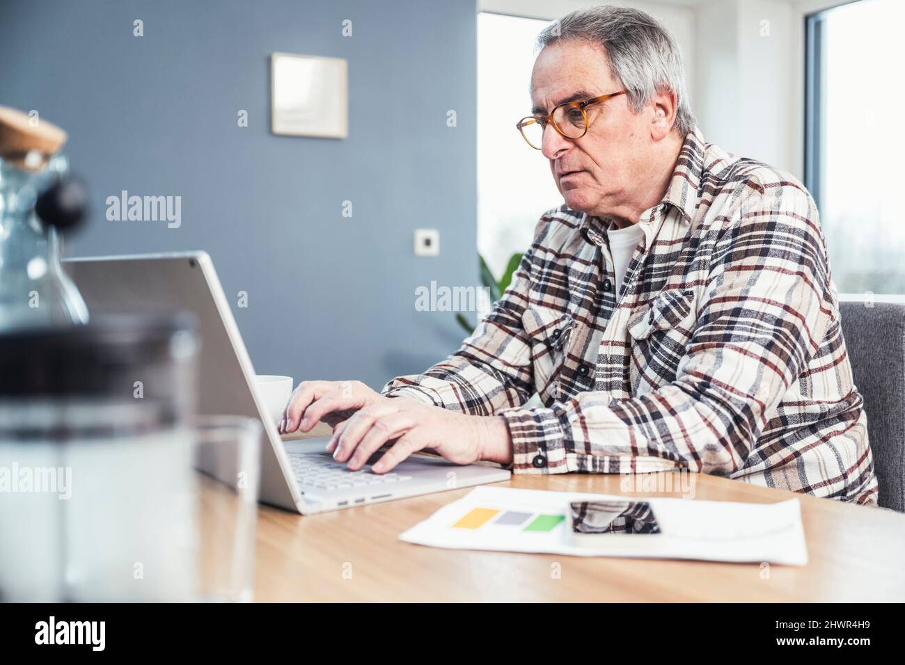 Man typing on laptop sitting at table Stock Photo