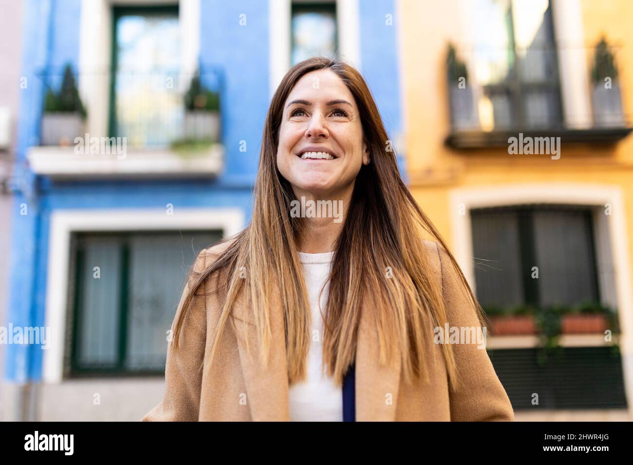 Smiling woman with long brown hair in city Stock Photo
