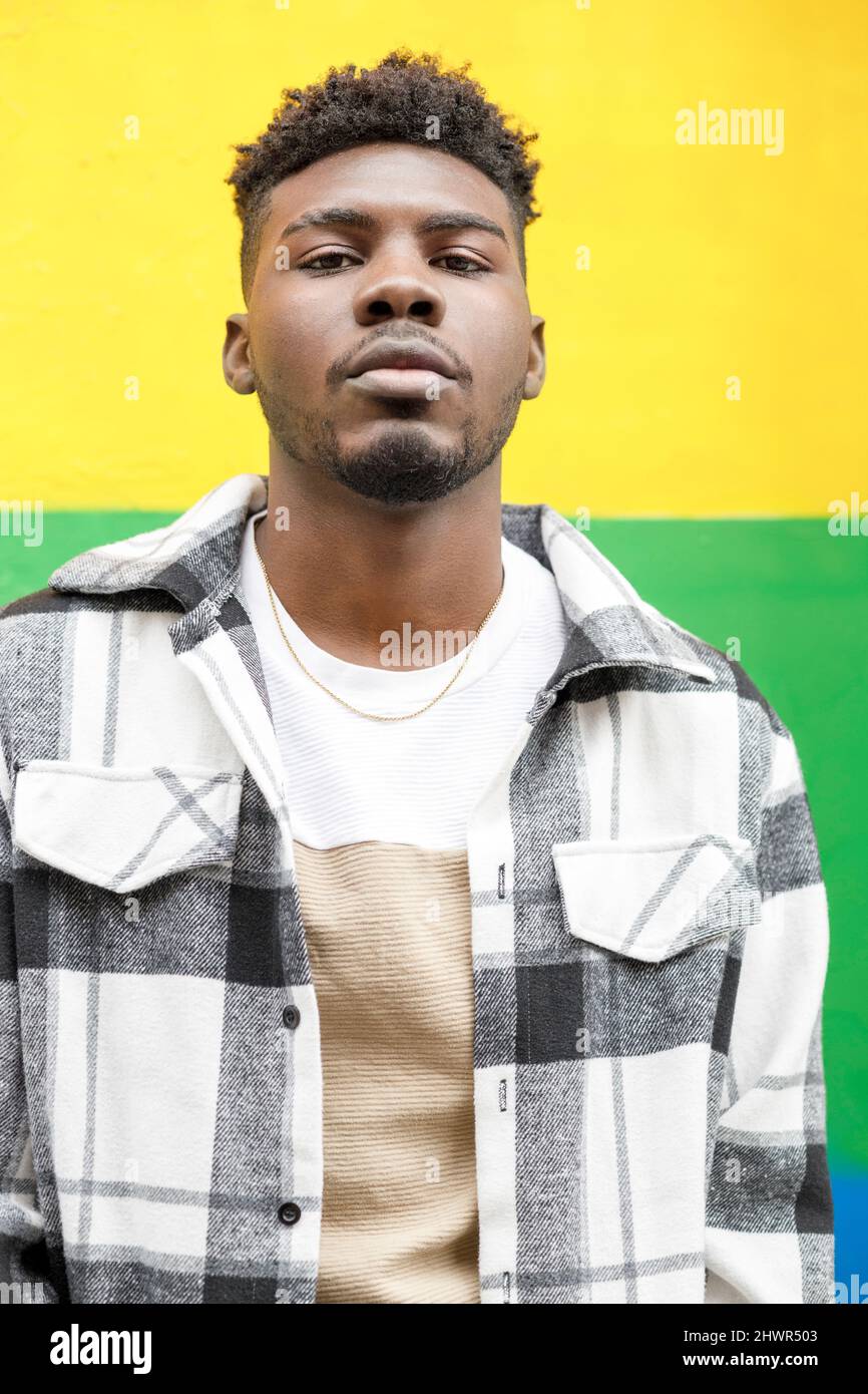 Young man standing in front of yellow and green wall Stock Photo - Alamy