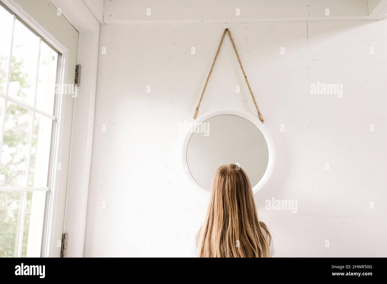 Blond girl standing in front of mirror at home Stock Photo